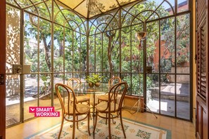 A glass-enclosed dining area with a table and chairs, surrounded by greenery. - Villetta Mezzarancia all Orto Botanico by Wonderful Italy (Palermo)