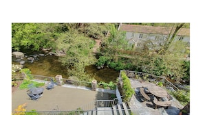 Un patio junto al río con mesas al aire libre y una escalera de piedra que baja hasta el agua.