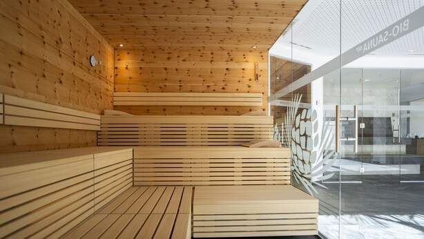 Un interior moderno con bancos de madera ranurada y un muro de cristal con un logotipo.