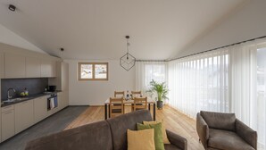 Una sala moderna con un sofá, un sillón y una mesa de comedor.