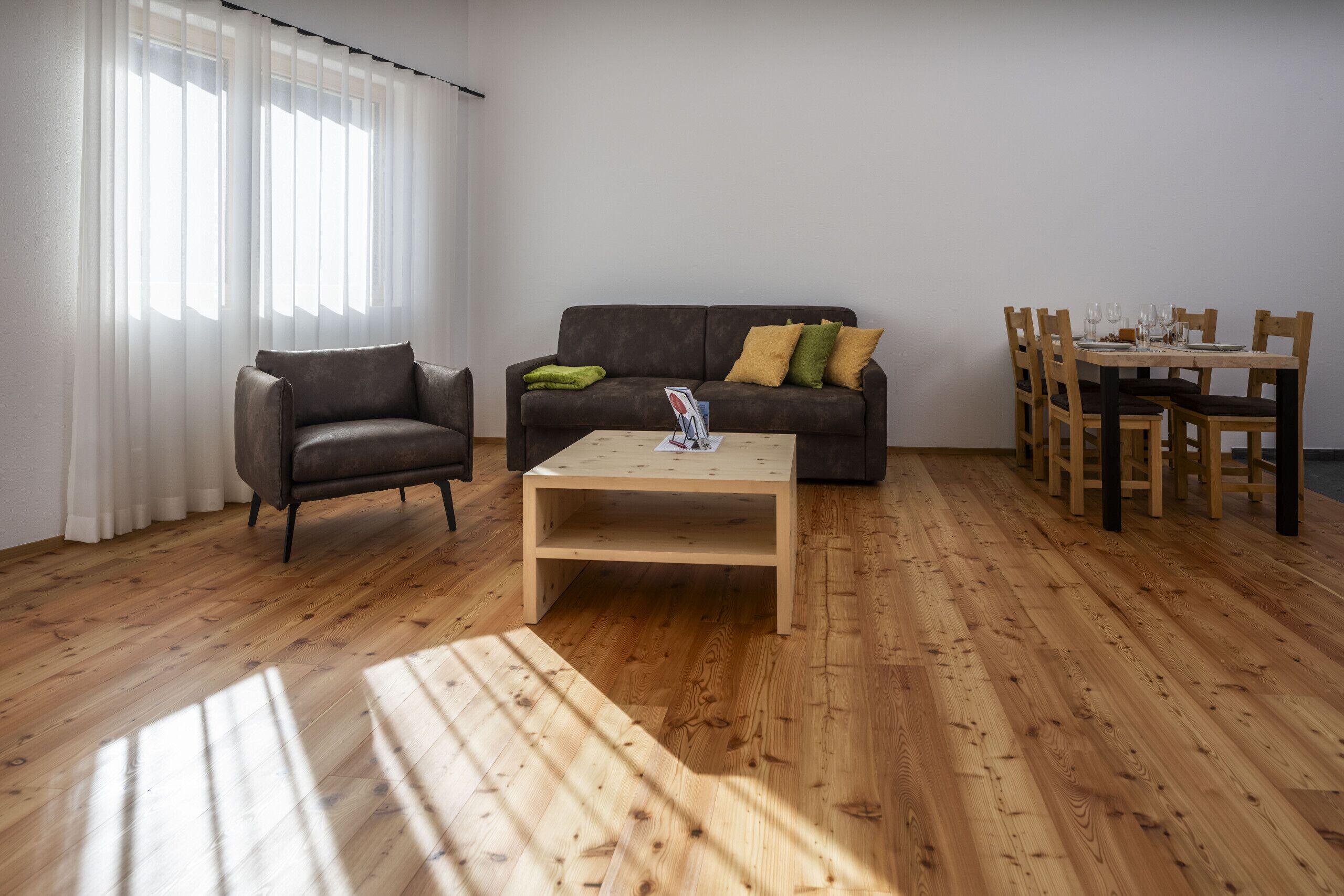 A living room with a sofa, a coffee table, and a dining table set with chairs.