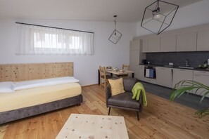 A compact living space with a bed, a sofa, a dining table, and a kitchenette. - Chasa Helvetia Studio: Relax and enjoy in the new studio with exclusive hotel service (Müstair)