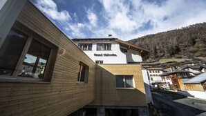 A hotel with a wooden facade, multiple windows, and a sign reading "Hotel Helvetia." - Chasa Helvetia Studio: Relax and enjoy in the new studio with exclusive hotel service (Müstair)