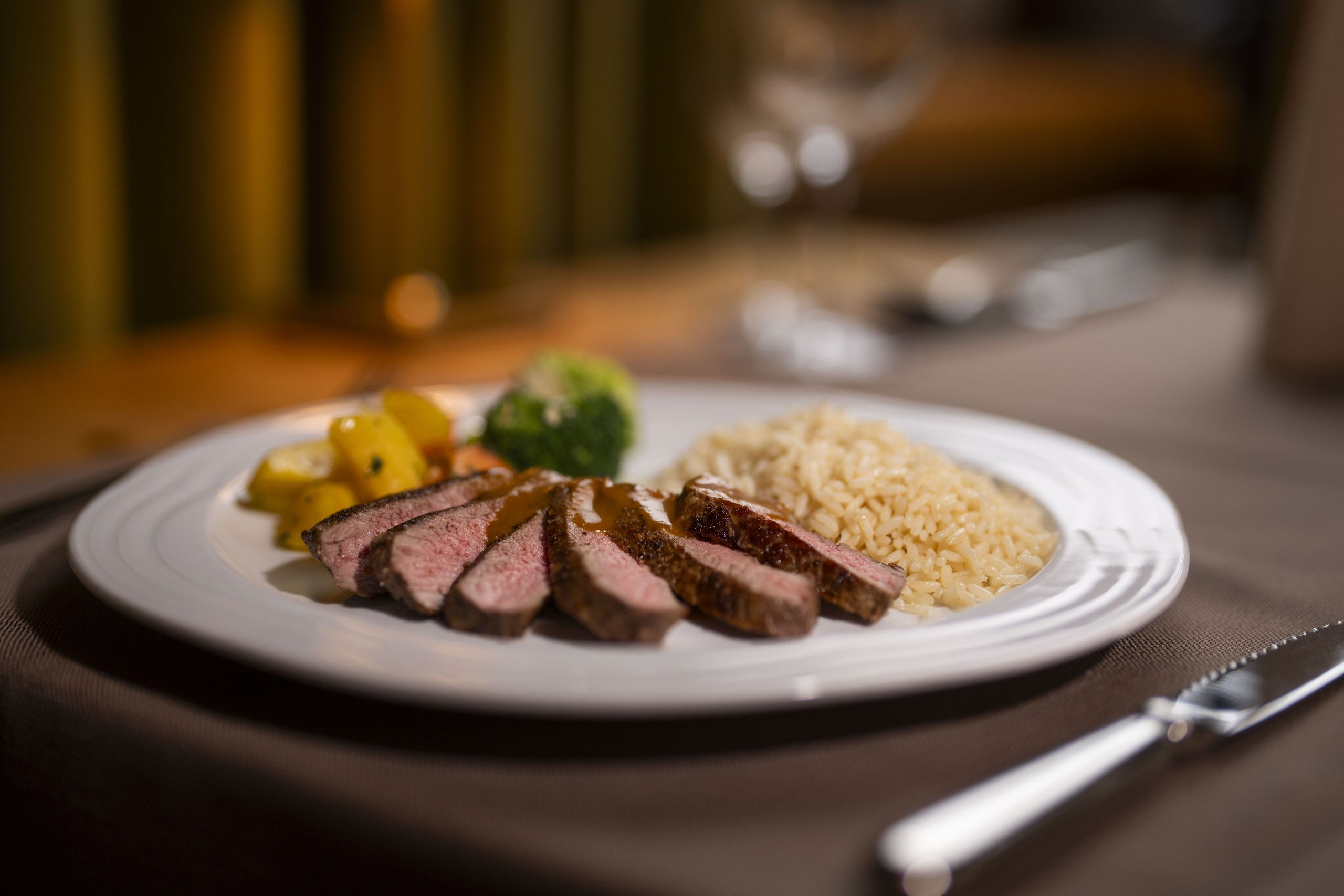Une assiette de nourriture contenant un steak, du riz et des légumes, posée sur une table.