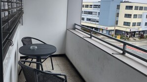 A balcony with a small table and two chairs, a window with metal bars, and a view of buildings in the background. - Eibacher Hof (Nuremberg)