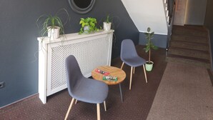 A modern reception area with a desk, two chairs, a round table, and potted plants. - Eibacher Hof (Nuremberg)
