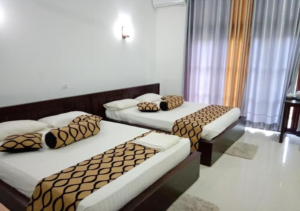 A hotel room with two beds, each with patterned bedspreads and matching pillows.