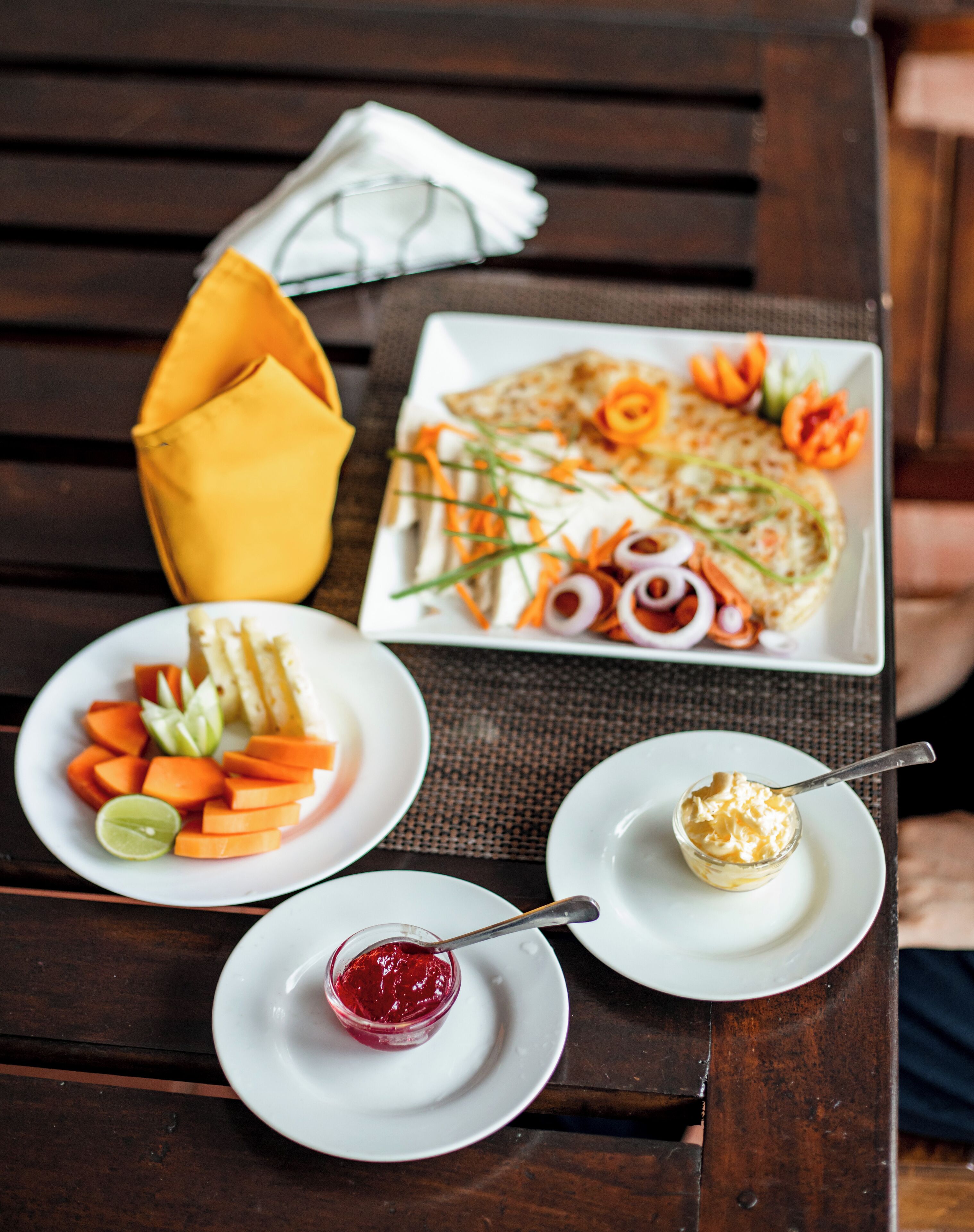 Una mesa con platos de comida, incluyendo una ensalada, fruta y un postre.