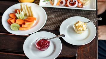 Una mesa con platos de comida, incluyendo una ensalada, fruta y un postre.