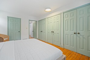 A bedroom with a bed, a wicker chair, and a wardrobe with multiple doors.