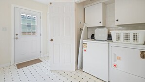 Cocina compacta con puerta blanca, ventana con persianas, lavadora y secadora.