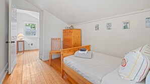 Un dormitorio con una cama de madera, una silla, un armario de madera y una mesita de noche con una lámpara.