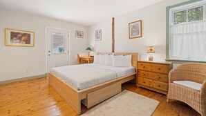 A bedroom with a wooden bed, a nightstand, a dresser, a chair, and framed pictures on the wall.
