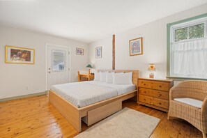 Un dormitorio con cama de madera, mesita de noche, cómoda, silla y cuadros en la pared.