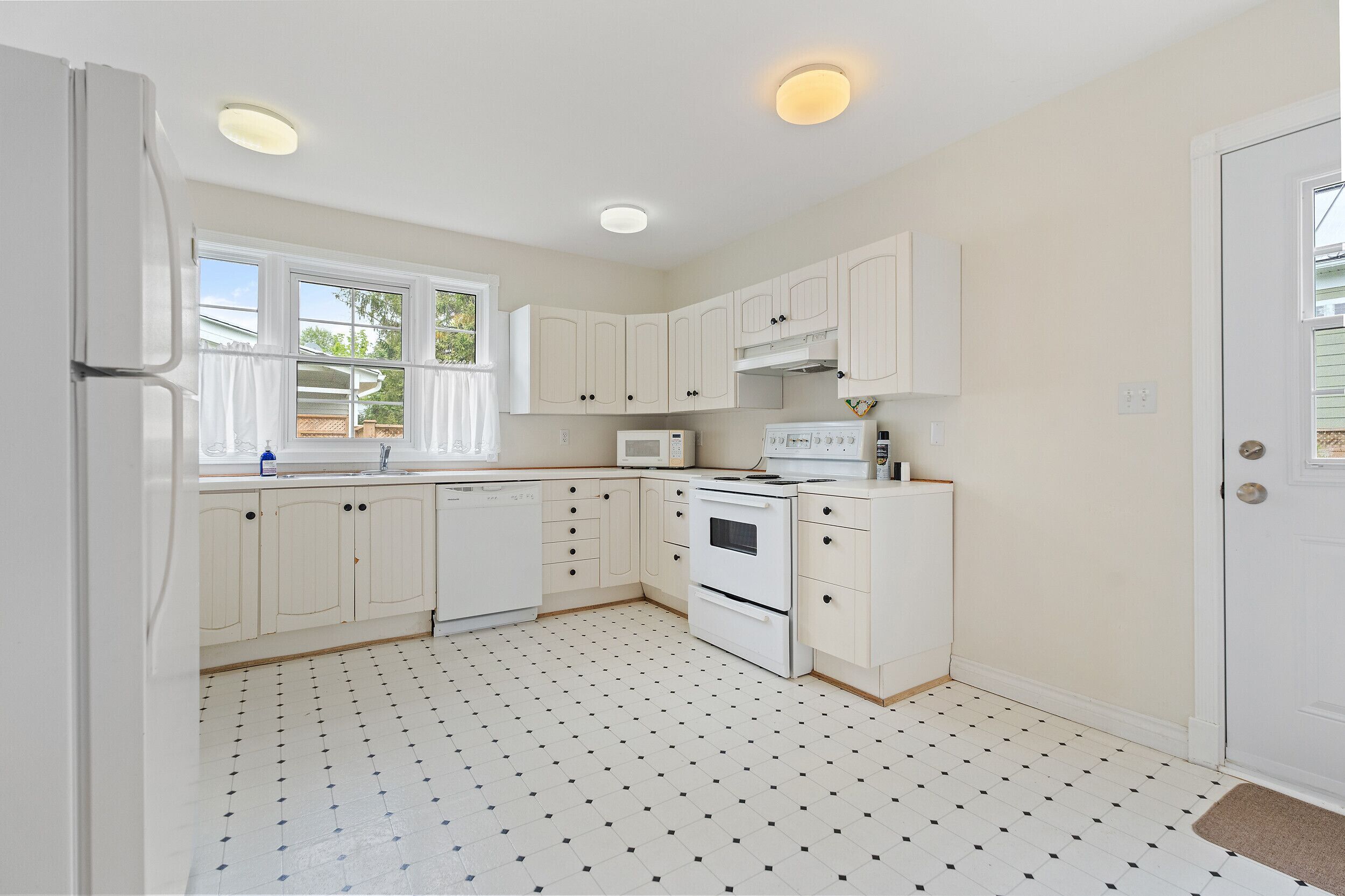 A compact kitchen with white cabinets, a microwave, an oven, and a refrigerator.