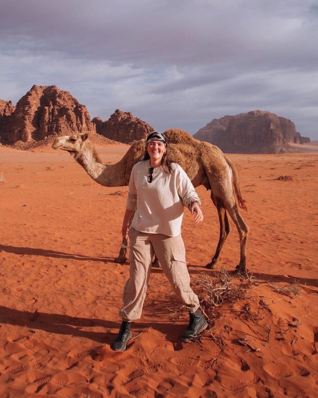 Una persona de pie en un desierto con un camello.