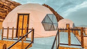 Two dome-shaped tents with wooden railings and a ramp leading to the entrance.