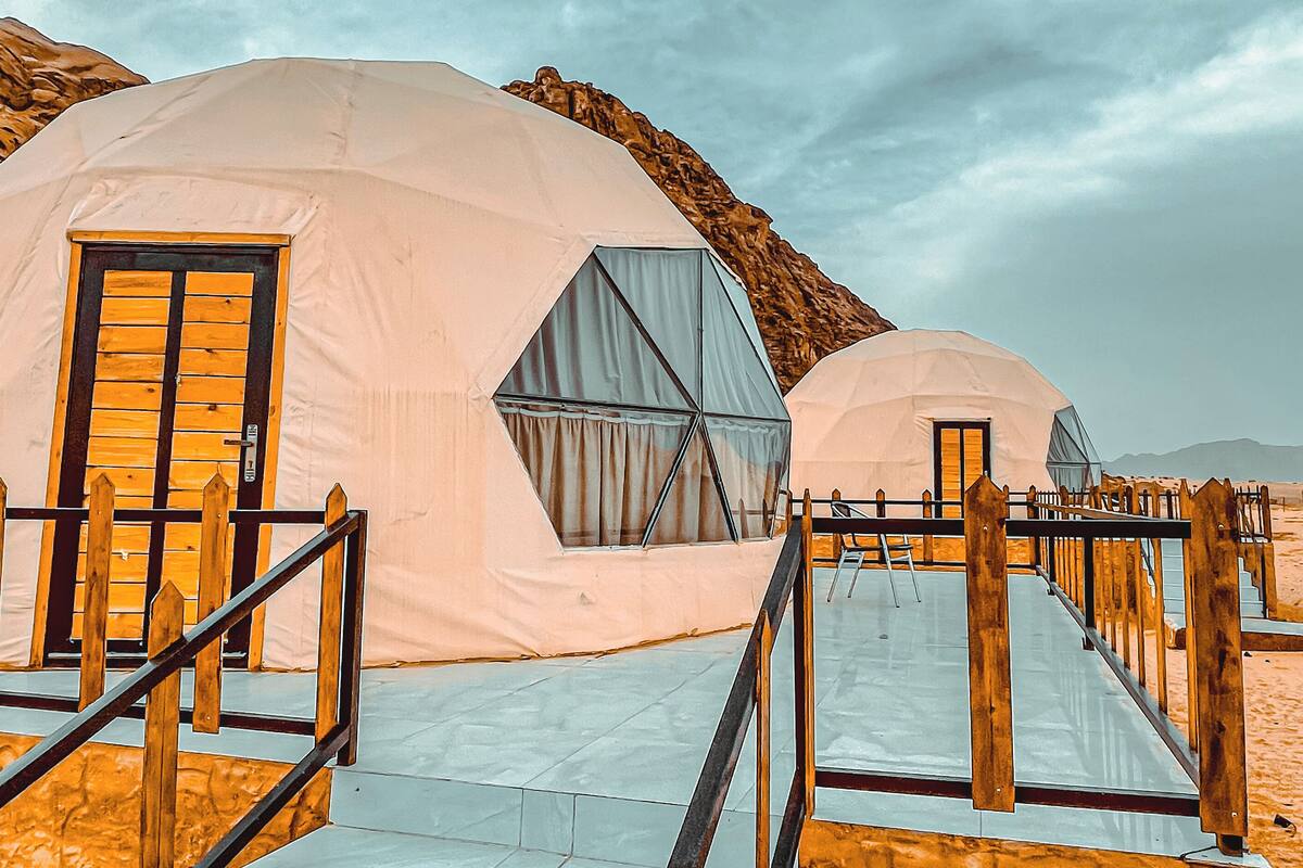 Two dome-shaped tents with wooden railings and a ramp leading to the entrance.