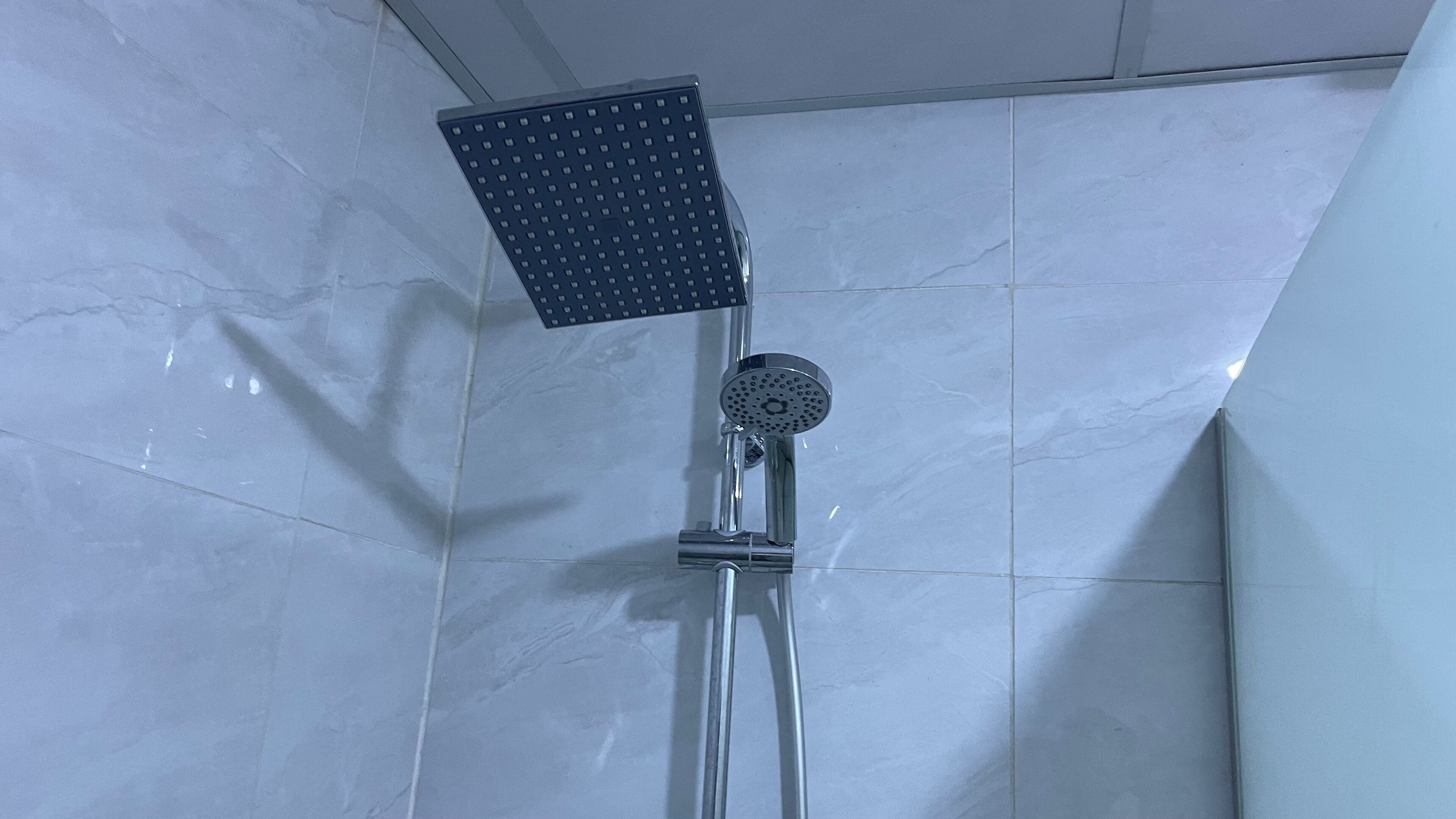 A shower with a square head and a round spout, mounted on a chrome fixture.