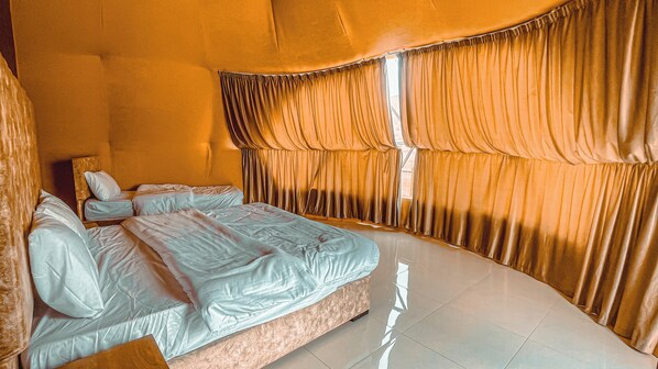 Un dormitorio con una cama grande, dos mesitas de noche y un ventanal con cortinas.