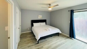 A bedroom with a bed, a ceiling fan, a window with curtains, and a door. - Sunny Getaway * 1BR condo close to the beach (B) (Myrtle Beach)