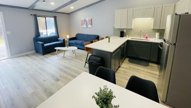 A modern kitchen with white cabinets, a stainless steel refrigerator, and a dining area with a white table and chairs. - Sunny Getaway * 1BR condo close to the beach (B) (Myrtle Beach)