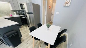 A modern kitchen with stainless steel appliances, a white dining table, and black chairs. - Sunny Getaway * 1BR condo close to the beach (B) (Myrtle Beach)