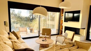 Una sala de estar moderna con un sofá, sillas, una mesa de centro redonda y un televisor montado en la pared.