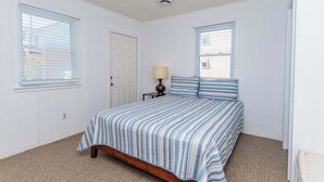 A bedroom with a bed, two windows, a door, and a lamp. - Midtown OC Unit 4/ Oceanblock / Sleeps 8 (Ocean City)