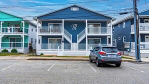 A two-story building with a prominent 'M' on the facade, a car parked in front, and a clear sky. - Midtown OC Unit 4/ Oceanblock / Sleeps 8 (Ocean City)