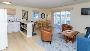 A modern living room with a dining area, kitchen, and a large window with blinds. - Midtown OC Unit 4/ Oceanblock / Sleeps 8 (Ocean City)