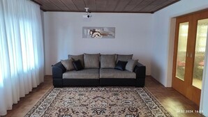 A living room with a sofa, a patterned rug, a ceiling fan, and a painting on the wall. - Completely Renovated House From 22 Euro pp and day (Baden-Baden)