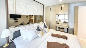 Une chambre d’hôtel avec un grand lit, une télévision, un miroir et une armoire.
