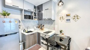 Une cuisine compacte équipée d’un réfrigérateur, d’un four à micro-ondes, d’un évier et d’un coin repas avec une table et des chaises.