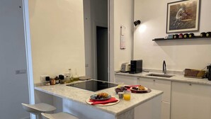 Una cucina moderna con un piano di lavoro in marmo, un tostapane integrato, un lavello e un piccolo angolo bar con sgabelli.