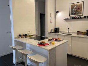 A modern kitchen with a marble countertop, a built-in toaster, a sink, and a small bar area with stools. - Rome Historic Center, near famed Piazza del Popolo (Rome)