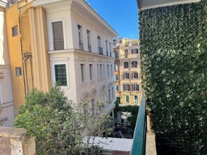 Ein mehrstöckiges Gebäude mit Balkonen, einem Innenhof mit Gartenmöbeln und einer grünen, blattbedeckten Wand.
