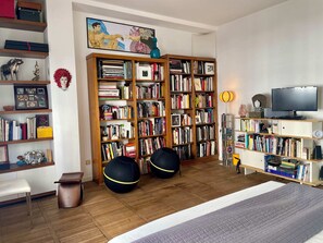 Ein Zimmer mit einem großen Bücherregal, einem Bett und einem Fernseher.