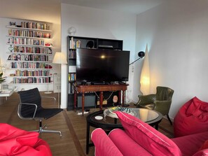 A living room with a flat-screen TV, a bookshelf, a coffee table, and red seating. - Rome Historic Center, near famed Piazza del Popolo (Rome)