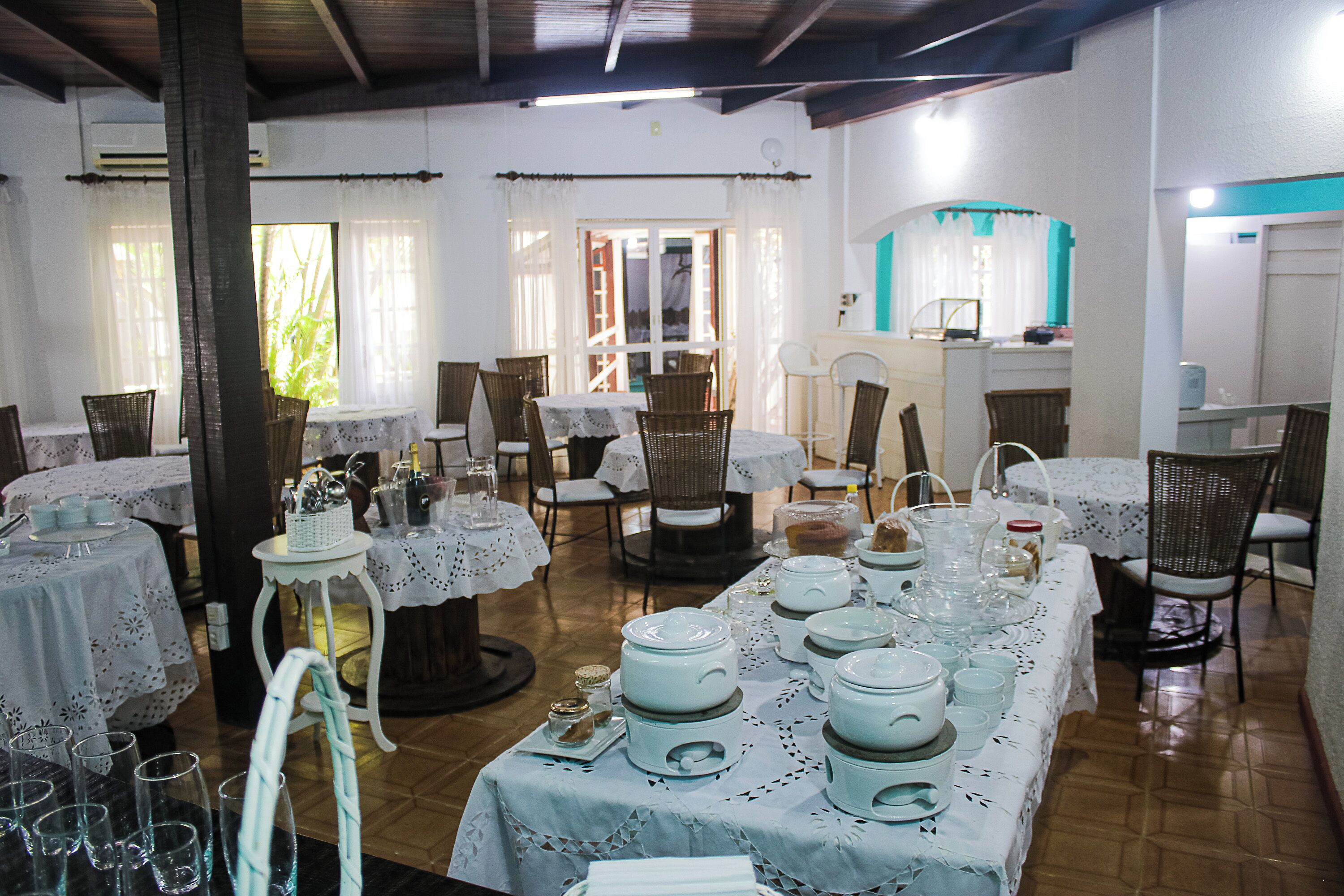 A dining area with multiple tables set for a meal, surrounded by wicker chairs.
