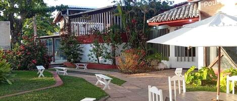 A courtyard with outdoor seating, a covered area, and a building with a tiled roof.