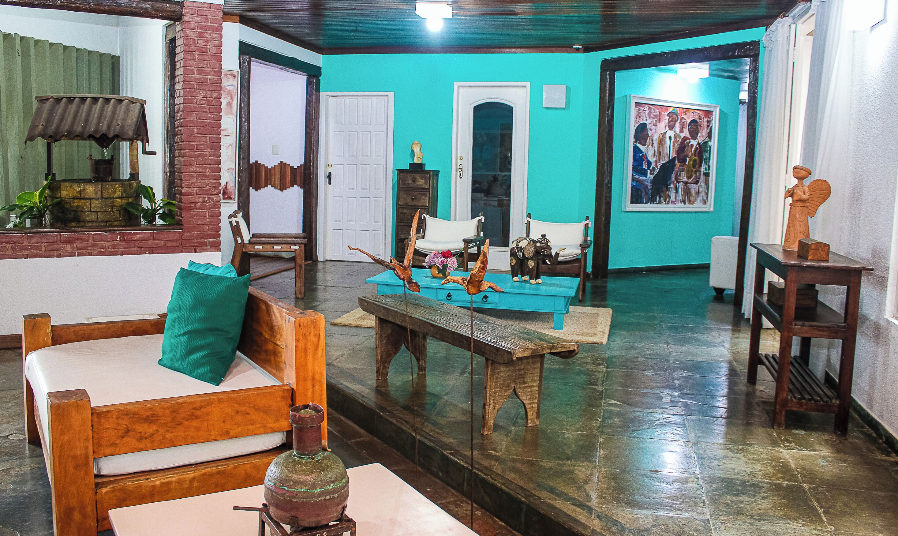 A room with a wooden bench, a table with decorative items, a door, and a painting on the wall.
