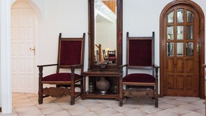 A room with two wooden chairs with red cushions, a tall wooden cabinet with a mirror, and a wooden door with glass panels. - Deluxe 3 Bd House near Lagonisi w Garden (Saronikos)