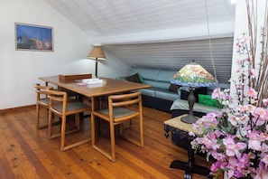 A cozy room with a wooden dining table and chairs, a sofa with cushions, a decorative lamp, and a painting on the wall. - Deluxe 3 Bd House near Lagonisi w Garden (Saronikos)
