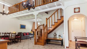 A spacious living area with a wooden staircase, a dining table with chairs, and a sofa. - Deluxe 3 Bd House near Lagonisi w Garden (Saronikos)