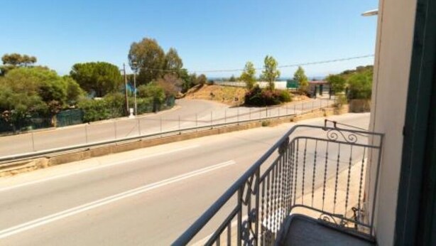 A balcony with a metal railing overlooking a road with a curve.