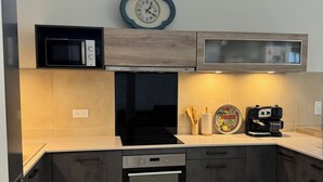 A modern kitchen with a built-in microwave, oven, and coffee maker.