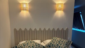 A neatly made bed with floral-patterned pillows, a headboard, and two wall-mounted lamps.