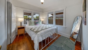 Ein Schlafzimmer mit einem Bett, Nachttischlampen, einem Deckenventilator, einem Fenster und einem Spiegel.
