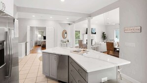 A modern kitchen with a large island, stainless steel appliances, and a dining area with a view.